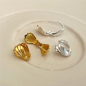 Macro detail of gold and silver shell-textured hoop earrings on a ceramic dish