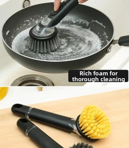 Détail de la brosse de cuisine à long manche nettoyant une poêle avec mousse riche