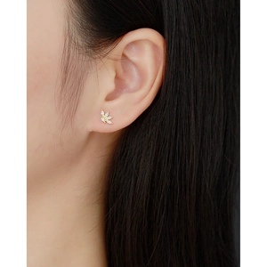 Elegant gold flower stud earrings with sparkling zircons worn by a model in a close-up view