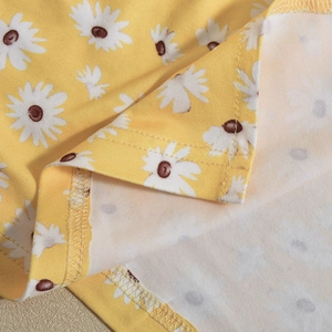 Vista macro del tessuto floreale giallo con stampa margherita e dettagli di cucitura