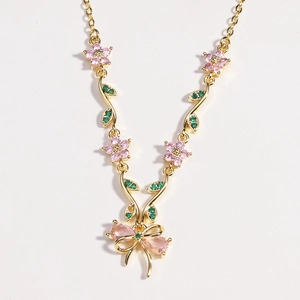 Detailansicht der goldenen Halskette mit rosa Blüten und einem rosa Edelstein-Schleifenanhänger