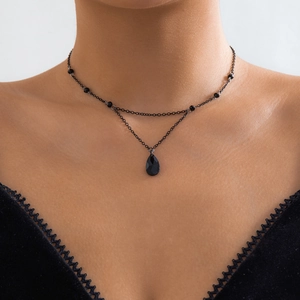 Detail of a gothic double-layer necklace with black faceted teardrop pendant on model