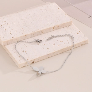 Detailed view of silver clover bracelet with small diamond on beige stone background