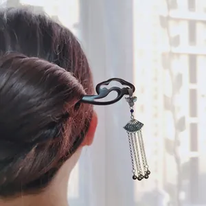 Modern geometric flower hair pin with ebony wood and fan tassel displayed in soft light