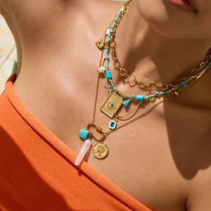 Close-up of layered gold necklace with turquoise beads, pink quartz and pearl details