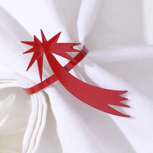 Détail d'un rond de serviette en métal rouge en forme de comète sur tissu blanc