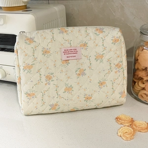 Detailed macro view of quilted floral cotton makeup bag featuring soft cream fabric textures