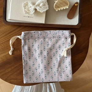 Close-up of a floral drawstring cotton pouch on a rustic wooden table with vintage decor