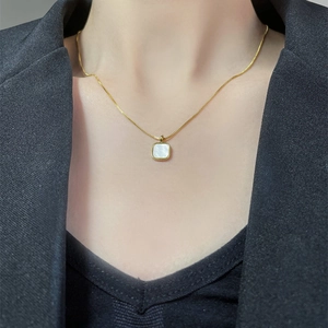 Collier en acier inoxydable plaqué or 14K avec pendentif carré en nacre porté par un mannequin