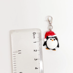 Vista detallada de un dije de pingüino navideño con cierre de langosta y una regla