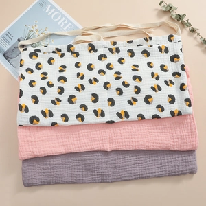 Close-up of stacked muslin cotton baby bibs with leopard print and solid colors in soft fabric