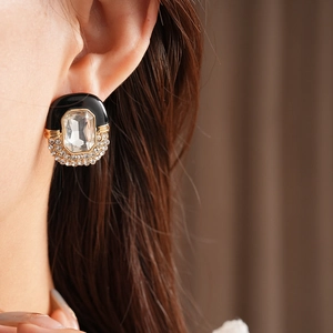 Close-up of vintage oval stud earrings with black enamel and sparkling rhinestones