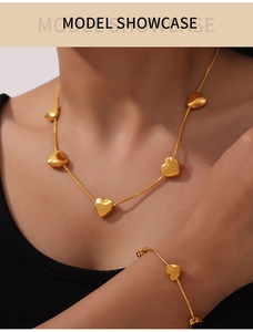 Detail of elegant gold heart pendant necklace and bracelet set on fashion model