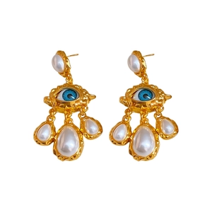 Vintage gold textured eye earrings with faux pearl teardrop charms on white background
