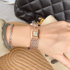 Close-up of rose gold padlock-shaped watch with mesh chain band on a model's wrist