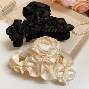 Detail of fabric ruffle hair claws in black and champagne silk textures on display