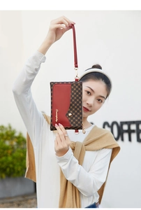 Detail of printed canvas and red leather clutch with gold metal logo and hand strap