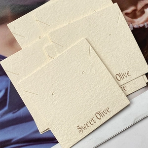 Macro view of textured cream specialty paper display cards for earrings and necklaces