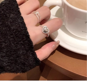 Silver heart ring and braided band worn by model in a cozy cafe social setting