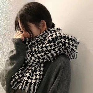 Close-up of black and white houndstooth scarf with soft fringe details on model