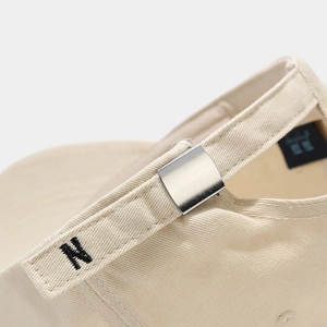 Detail of beige cotton baseball cap featuring silver metal buckle and N letter embroidery