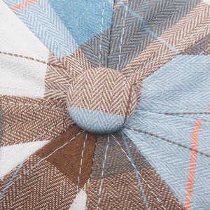 Detailed top view of vintage plaid beret with colorful patchwork fabric and decorative button