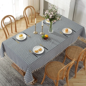 Detail of grey rectangular tablecloth featuring white herringbone patterns and tassel edges