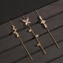 Detail of three gold earrings with zircons in lightning, flower, and star shapes