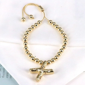 Detail of adjustable gold bead bracelet featuring a sparkling X pendant with zircons