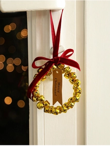 Golden Christmas bell ring with red velvet bow and Merry Christmas tag on window