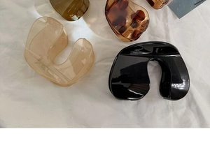 Flat lay of U-shaped hair claws in beige, black, and tortoise shell on white fabric
