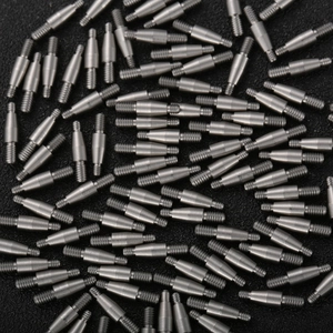 Precision stainless steel double-ended threaded studs scattered on a textured background