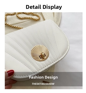 Close-up of white saddle bag with sunburst stitching and gold metal twist lock detail