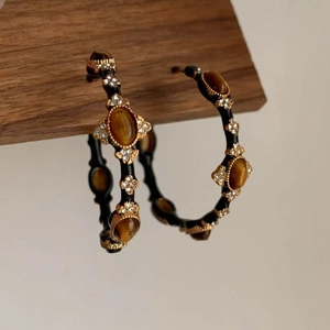 Macro view of vintage style gold-rimmed black hoop earrings with amber stones and crystals