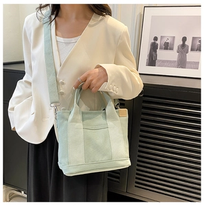 Detail of light green canvas tote bag with adjustable wide strap and dual handles