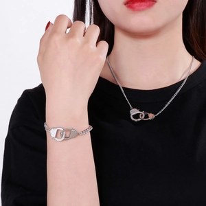 Detail view of silver stainless steel handcuff necklace and bracelet set on a model