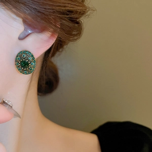 Close-up of vintage emerald green crystal earrings worn by model for elegant display