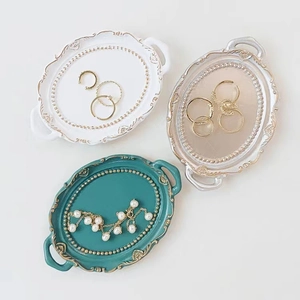 Three elegant oval resin jewelry trays in white, silver, and peacock green with gold trim