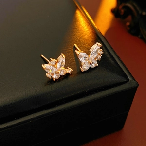 Vue macro de boucles d'oreilles papillon dorées avec cristaux étincelants sur cuir noir