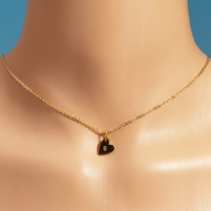 Gros plan du pendentif cœur doré avec la lettre B gravée sur une chaîne délicate