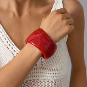 Close-up of red resin geometric wide bangle worn with white crochet knit clothing