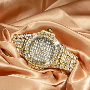 Close-up of gold-plated watch with square-cut crystal embellishments on golden satin cloth