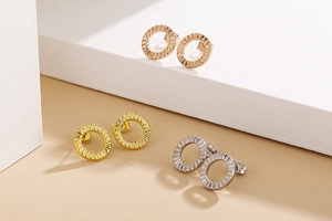 Detailed close-up of textured round hollow earrings in rose gold, gold and silver finishes