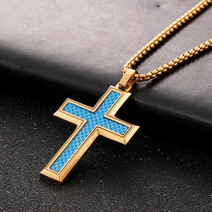 Detail of golden cross pendant with blue carbon fiber inlay on black leather surface