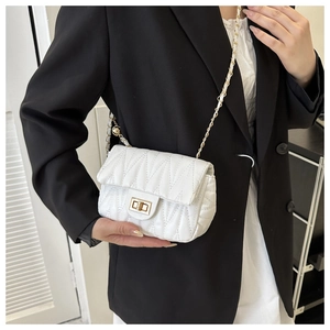 Close-up of white quilted crossbody bag featuring metal chain strap and turn-lock closure