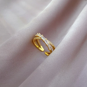 Macro shot of gold-plated crossover ring with pavé zircons on purple silk fabric