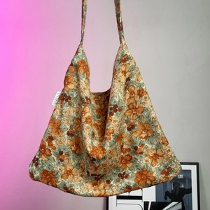 Detail of vintage floral canvas tote bag in orange and green with MAUD brand tag