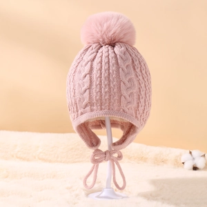 Close-up of pink cable knit texture on a baby winter hat with earflaps and pom pom