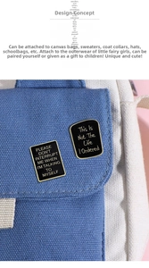 Detailed view of black enamel rectangle badges with gold trim on a blue canvas bag