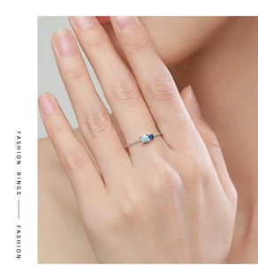 Detail of S925 silver ring on finger with asymmetric light and dark blue zircons